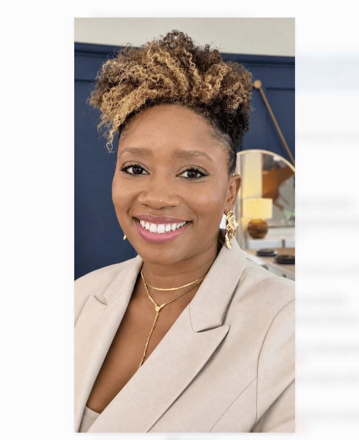 Smiling Black woman with short curly blonde-highlighted hair, wearing a tan blazer and gold jewelry.